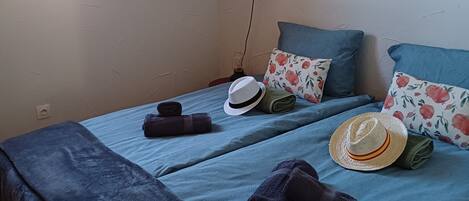 Ein Zimmer mit zwei Betten, einem Fenster und einem an der Wand hängenden Bild.