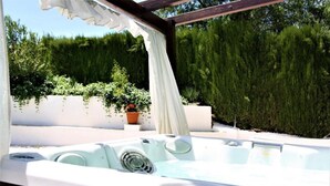 A hot tub with a control panel, surrounded by greenery and a white pergola. - Casita of Casa Olivar (Tocón)