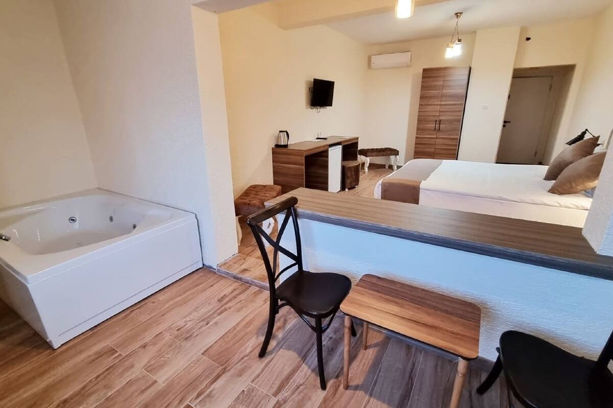 Une salle de bain moderne avec une baignoire, un banc en bois et une petite table.