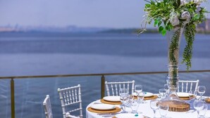 A table set for a meal with white chairs, a clear view of the water, and a decorative vase with greenery. - La Pearl Konaklama (Istanbul)