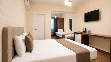 A hotel room with a bed, a desk, a television, and a door leading to a bathroom.