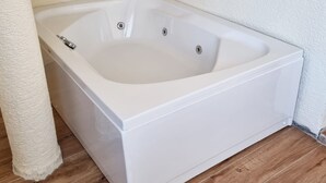 A white freestanding bathtub in a corner with a wooden floor and white textured walls. - La Pearl Konaklama (Istanbul)