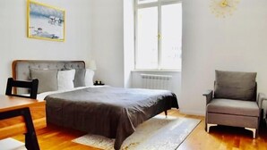 Un dormitorio moderno con cama, una silla, una mesa y un ventanal.