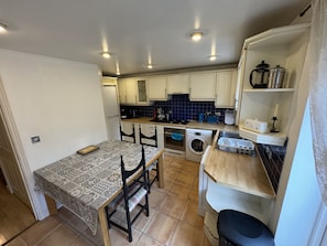 Een praktische keuken met een eethoek, inclusief een tafel, stoelen, een wasmachine en een spoelbak.
