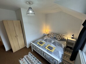 Een slaapkamer met een bed, nachtlampjes, een kledingkast en een hanglamp.