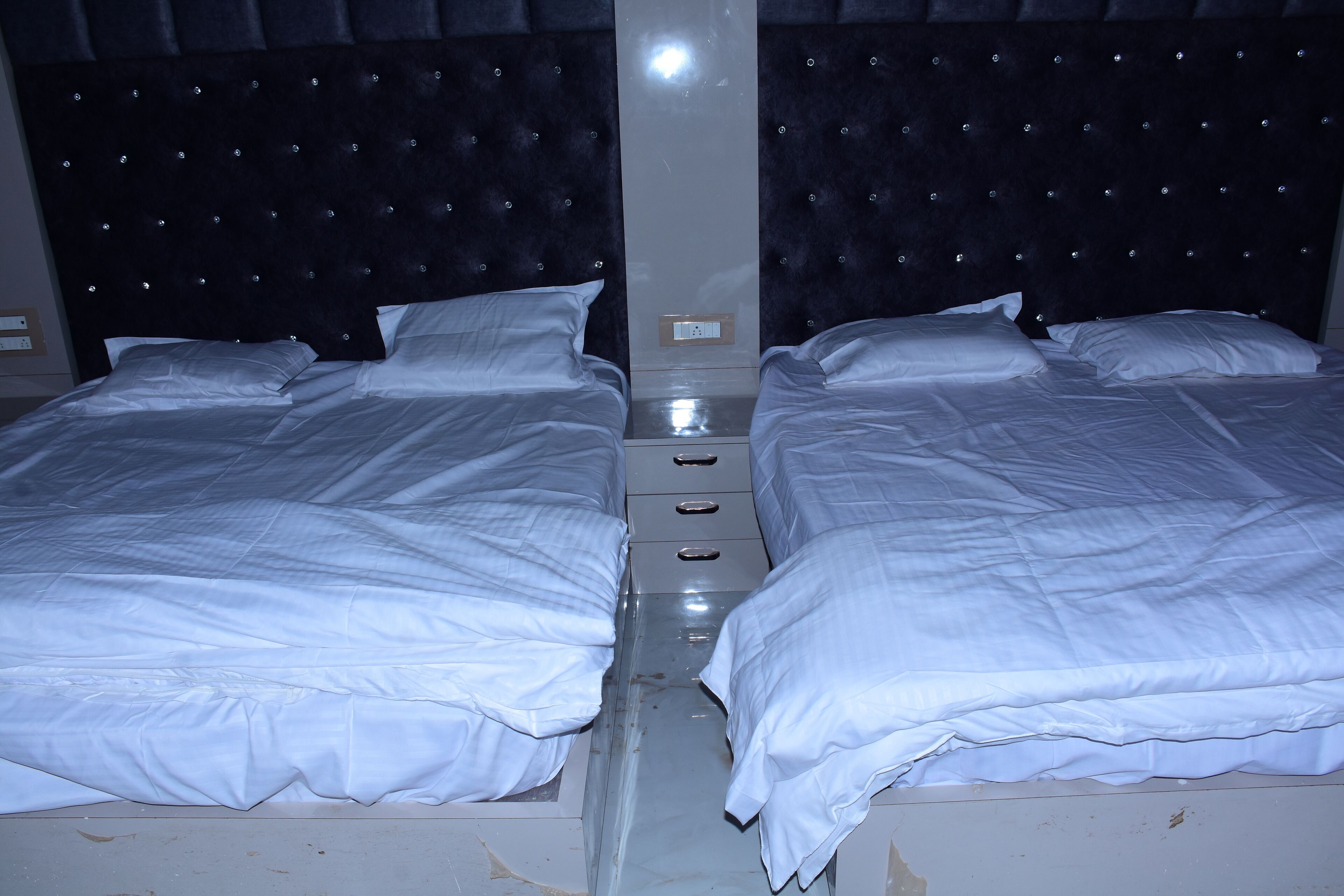 A double bed with a headboard, a nightstand, and a power outlet.