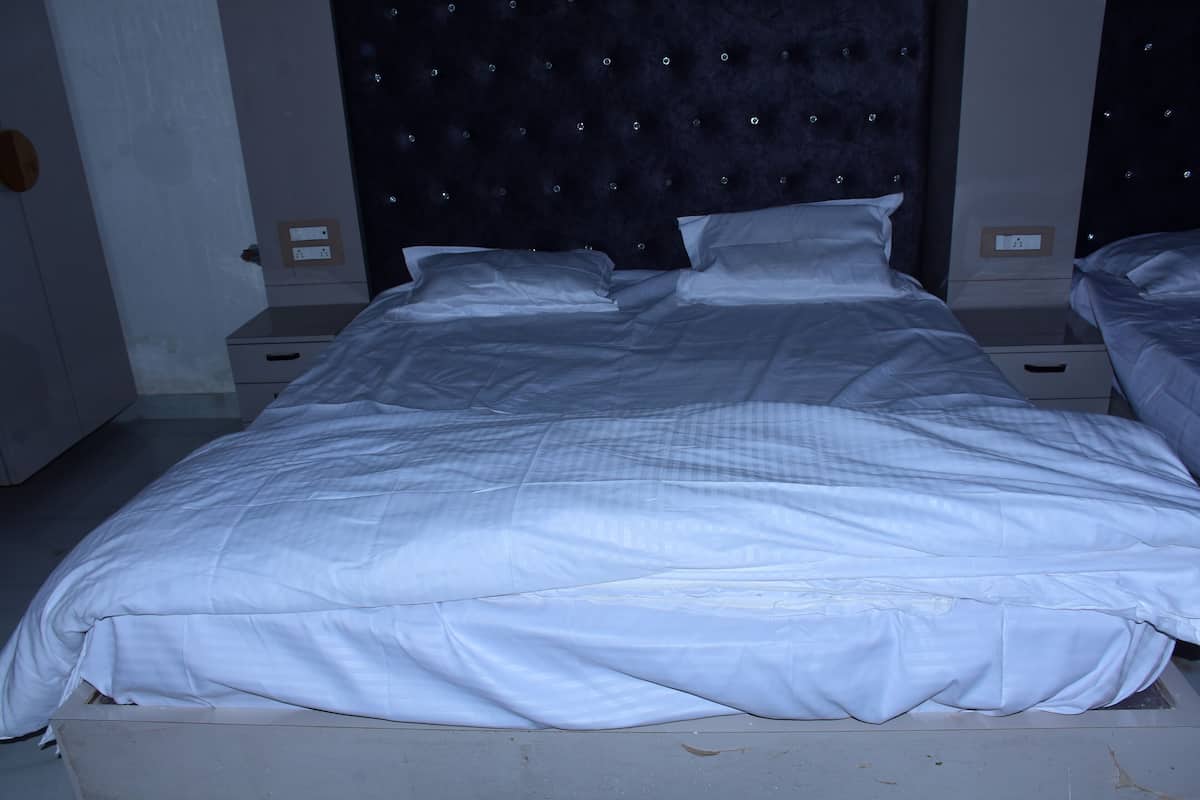 Ein Bett mit weißer Bettwäsche, einem gebügelten Kopfteil und Nachttischen mit Lampen.