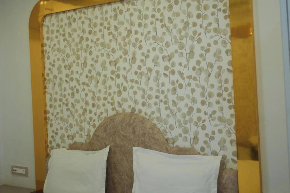 Ein Schlafzimmer mit einem Bett, einem Blattmuster an der Kopfteil und einer Deckenleuchte.