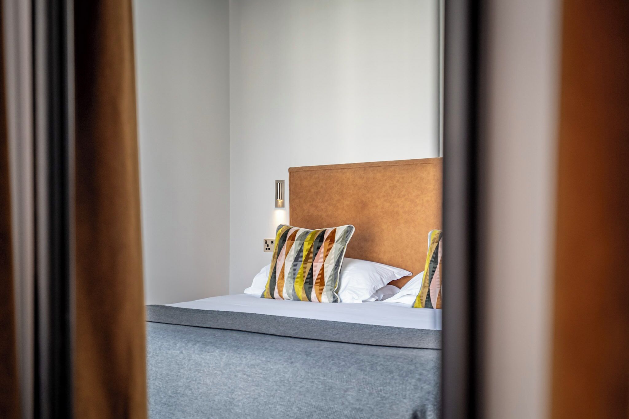 A hotel room with a bed, a headboard, and a bedside table.