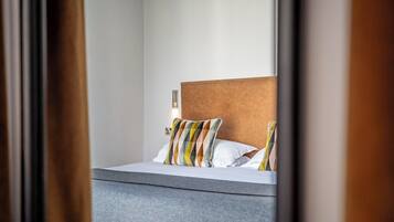 A hotel room with a bed, a headboard, and a bedside table.
