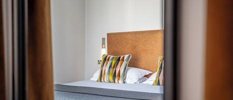 A hotel room with a bed, a headboard, and a bedside table.