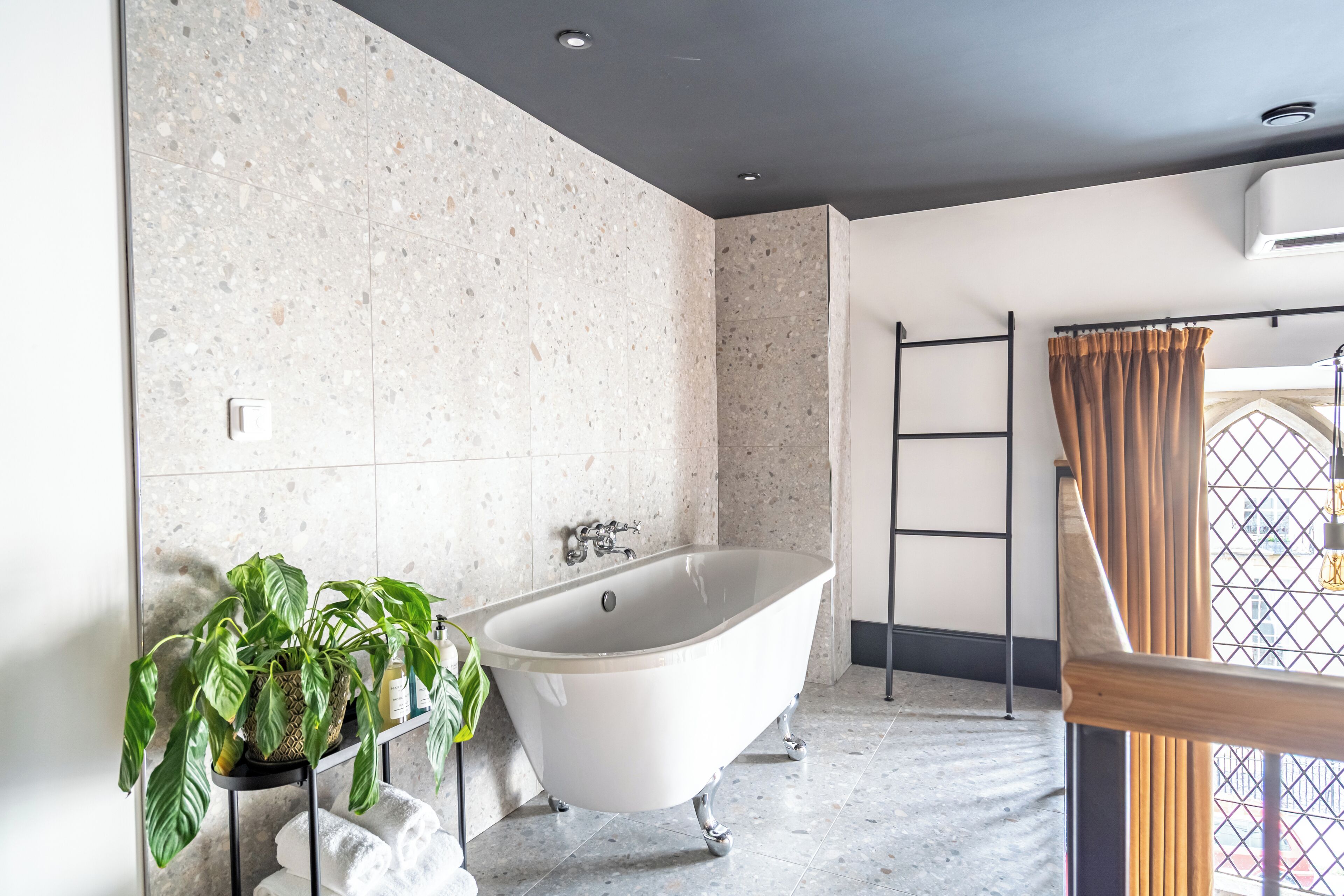 A bathroom with a freestanding bathtub, a potted plant, and a towel rack.