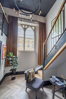 Un interior moderno con una escalera, un banco, una planta en maceta y una mesa con un control remoto.