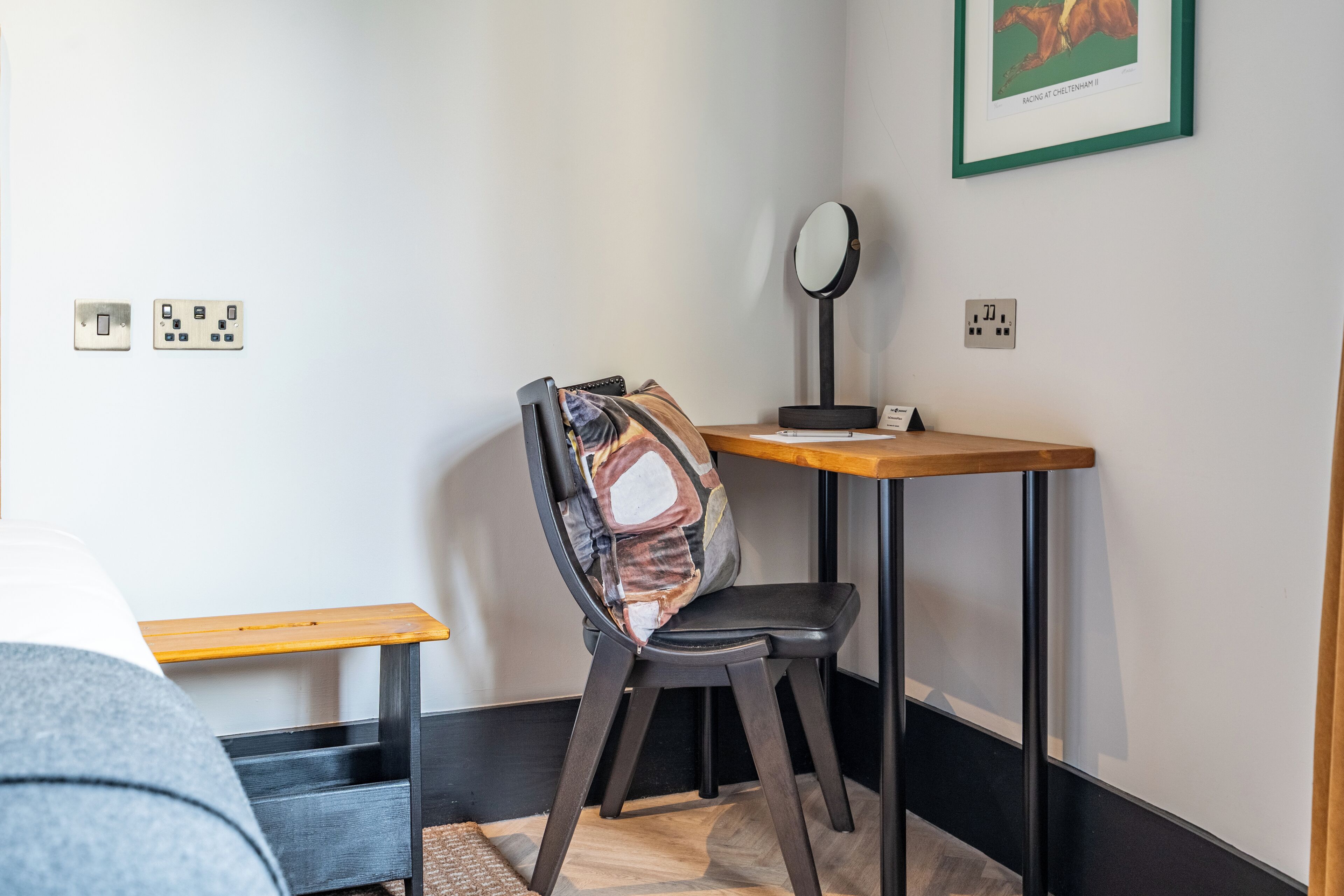 Een kleine, verzorgde kamer met een bureau, stoel en een bed.