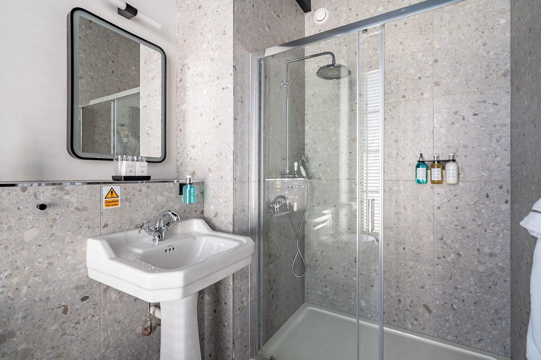 Un baño moderno con ducha de vidrio, lavamanos y espejo.