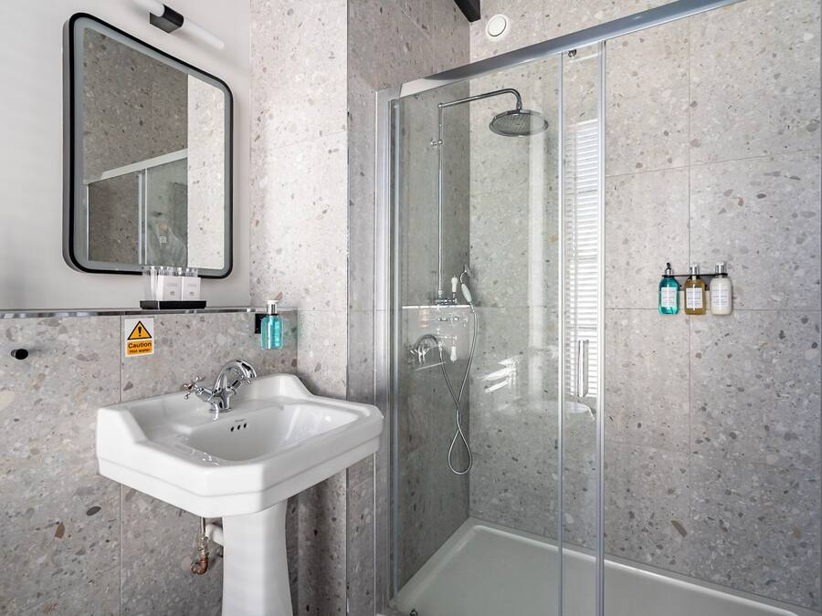 Un baño moderno con ducha de vidrio, lavamanos y espejo.