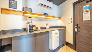A modern kitchen with a built-in coffee maker, a kettle, and a white refrigerator.