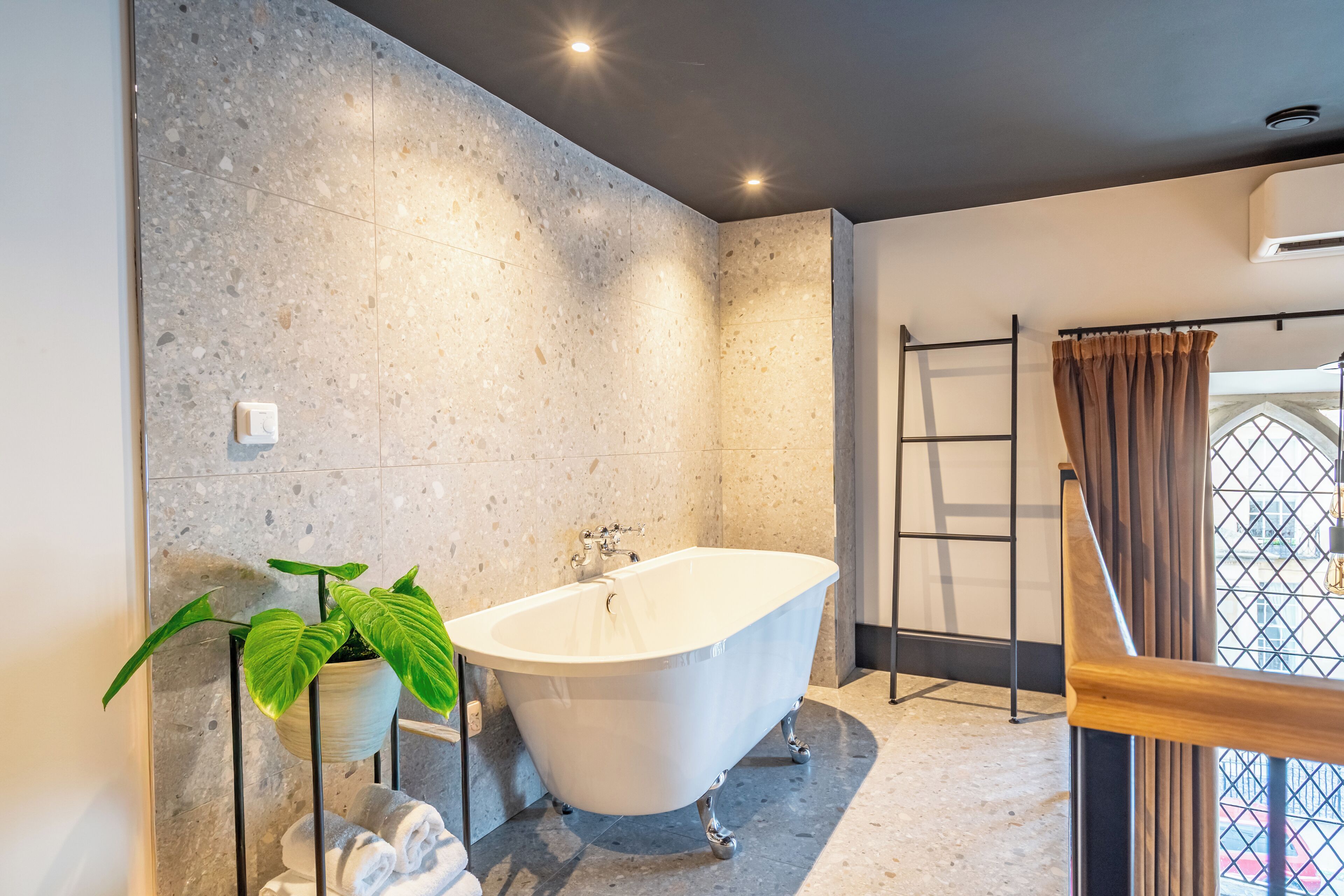 Ein modernes Badezimmer mit einer freistehenden Badewanne, einem Topfpflanzen und einem Handtuchhalter.