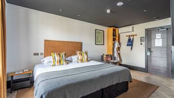 A modern hotel room with a large bed, a wooden headboard, a wardrobe, and a door with a handle.