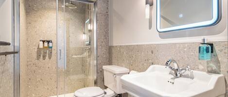 Ein modernes Badezimmer mit einer gläsernen Duschkabine, einer weißen Toilette und einem Waschbecken mit Spiegel darüber.