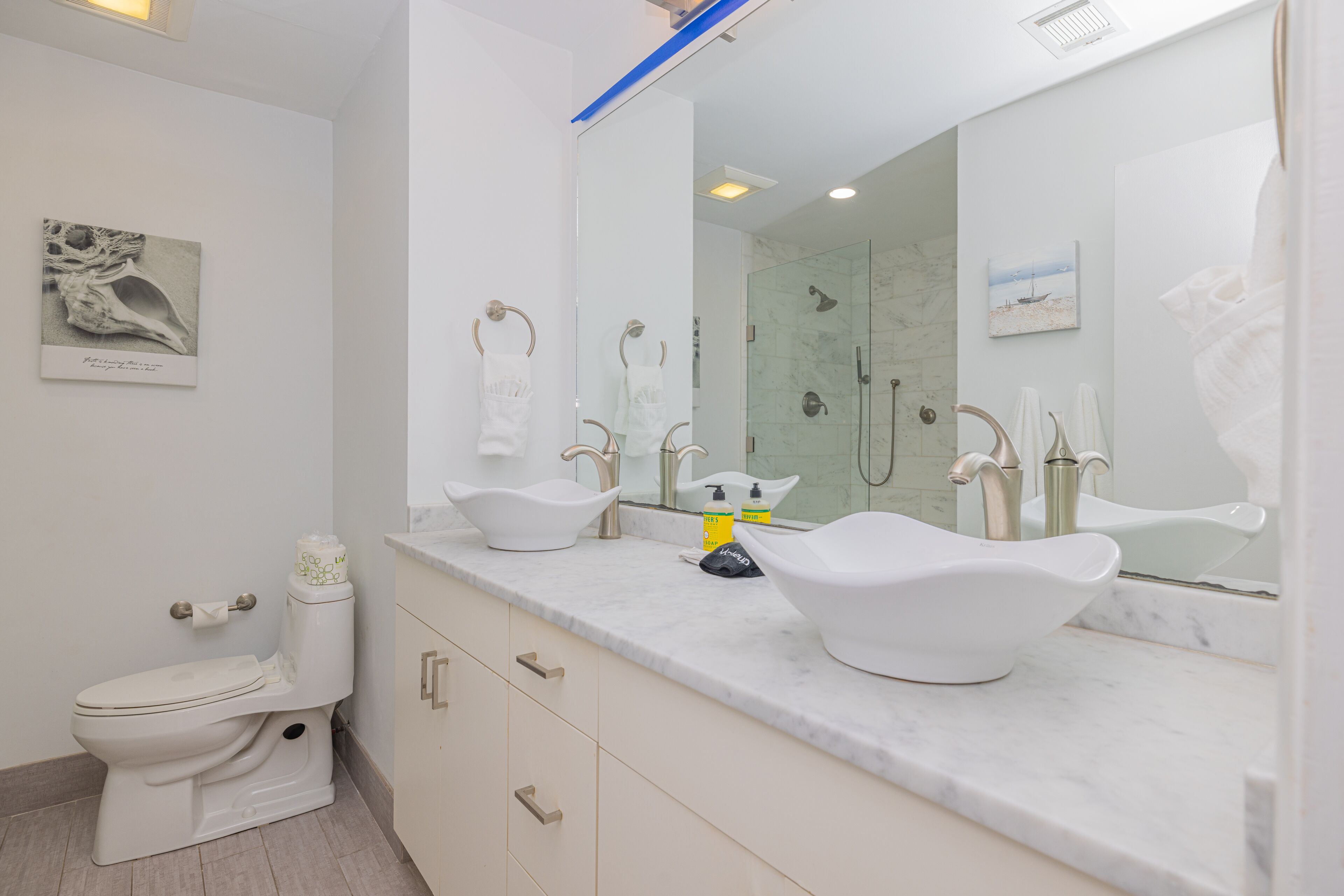 Un baño moderno con lavamanos, tocador y retrete blancos.