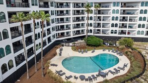 A multi-story hotel with a central pool area surrounded by lounge chairs and palm trees. - Oceanfront Condo in Wild Dunes! Community Pool! Great View Looking at Ocean! (Isle Of Palms)