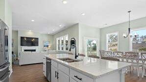 A modern kitchen with a central island, built-in appliances, and a dining area with a view.