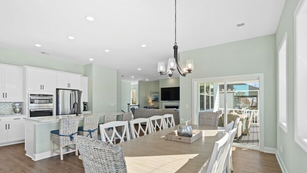 A spacious kitchen with white cabinets, a dining area with a wooden table and chairs, and a large island with seating.