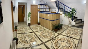 A reception area with a wooden desk, a blue staircase, and patterned flooring. - Hostel Jaz (Bucharest)