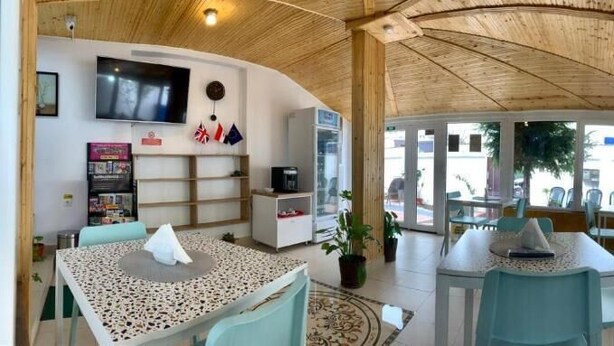 A spacious indoor area with a high ceiling, a television mounted on the wall, and a seating area with tables and chairs. - Hostel Jaz (Bucharest)
