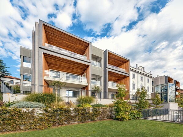 A modern multi-story building with balconies and a garden area in front. - Residenza Montebello (Verbania)