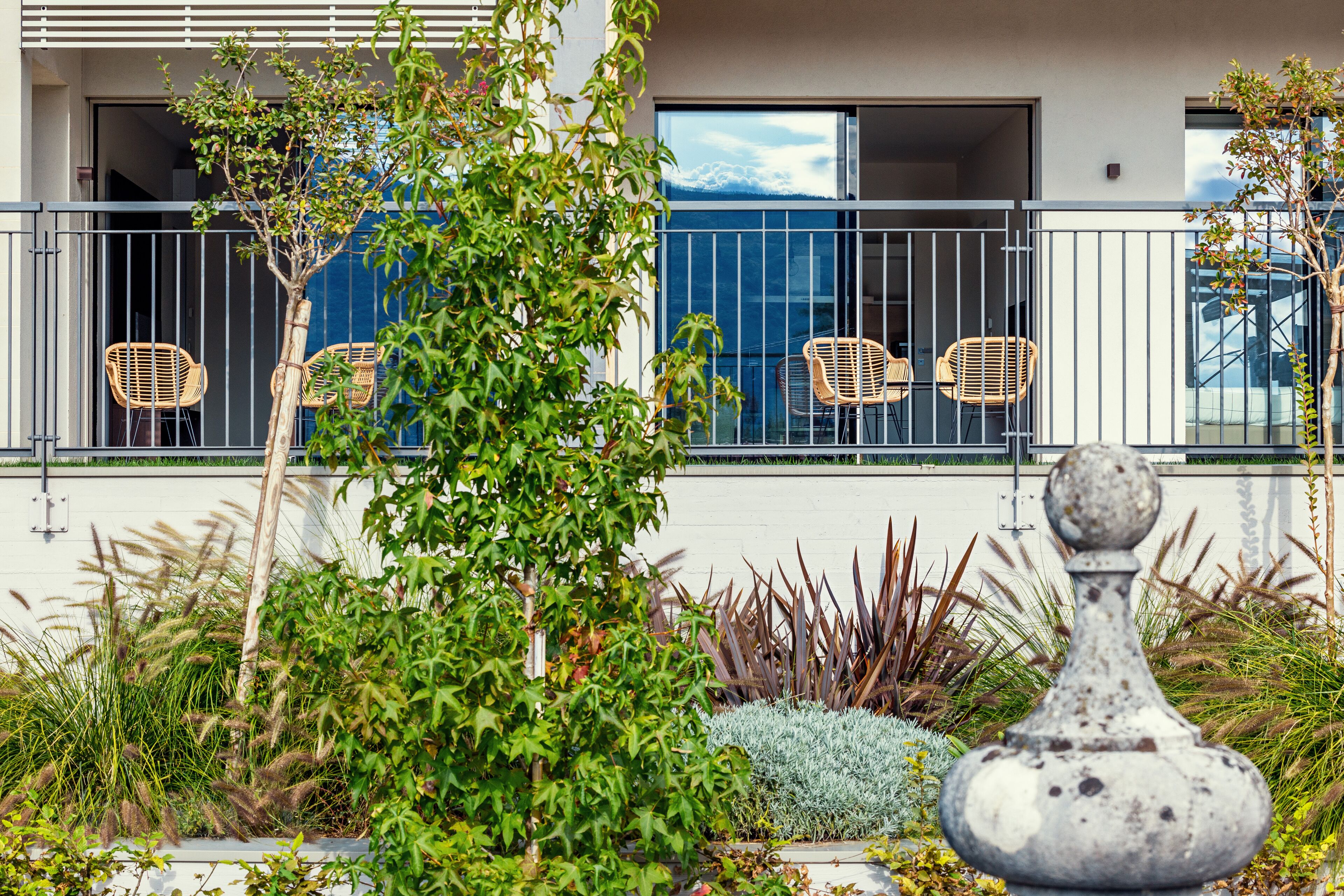 A balcony with wicker chairs, a small tree, and a decorative stone planter.