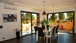 Un espace repas moderne avec une cloison en verre, des chaises noires et blanches, une table et un luminaire suspendu.