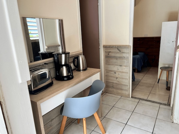 A compact kitchenette with a coffee maker, toaster, and kettle on a wooden countertop.