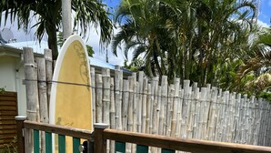 A wooden gate with a surfboard and safety signs.