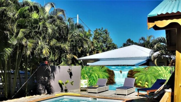 A swimming pool with lounge chairs, a waterfall feature, and tropical vegetation.