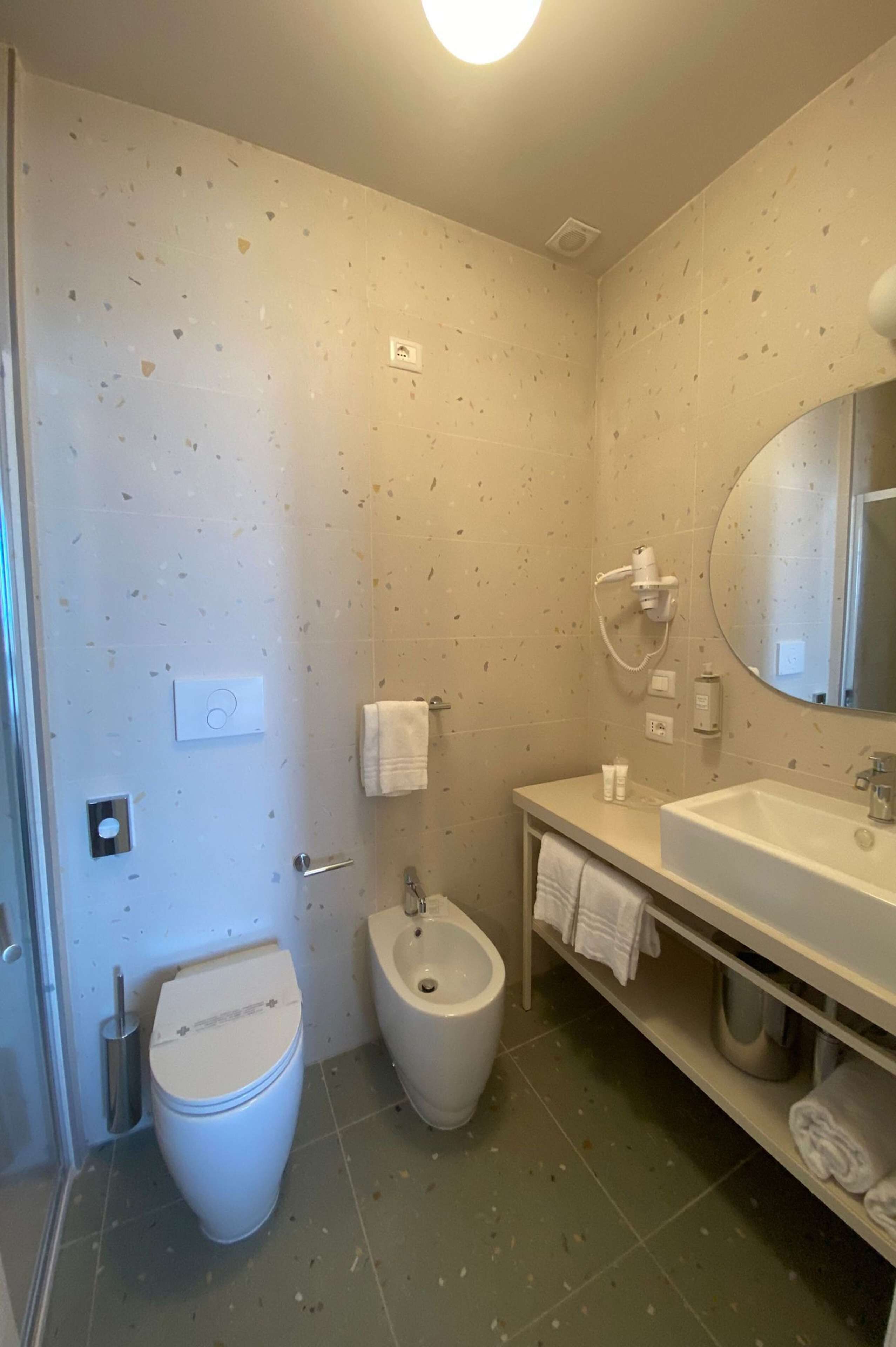 A bathroom with a toilet, bidet, sink, and a mirror.
