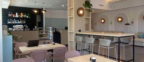 A modern restaurant with multiple tables and chairs, a bar area, and a counter with a display of bottles.