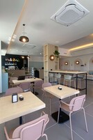 Un restaurante moderno con varias mesas y sillas, una zona de bar y un mostrador con una exhibición de botellas.