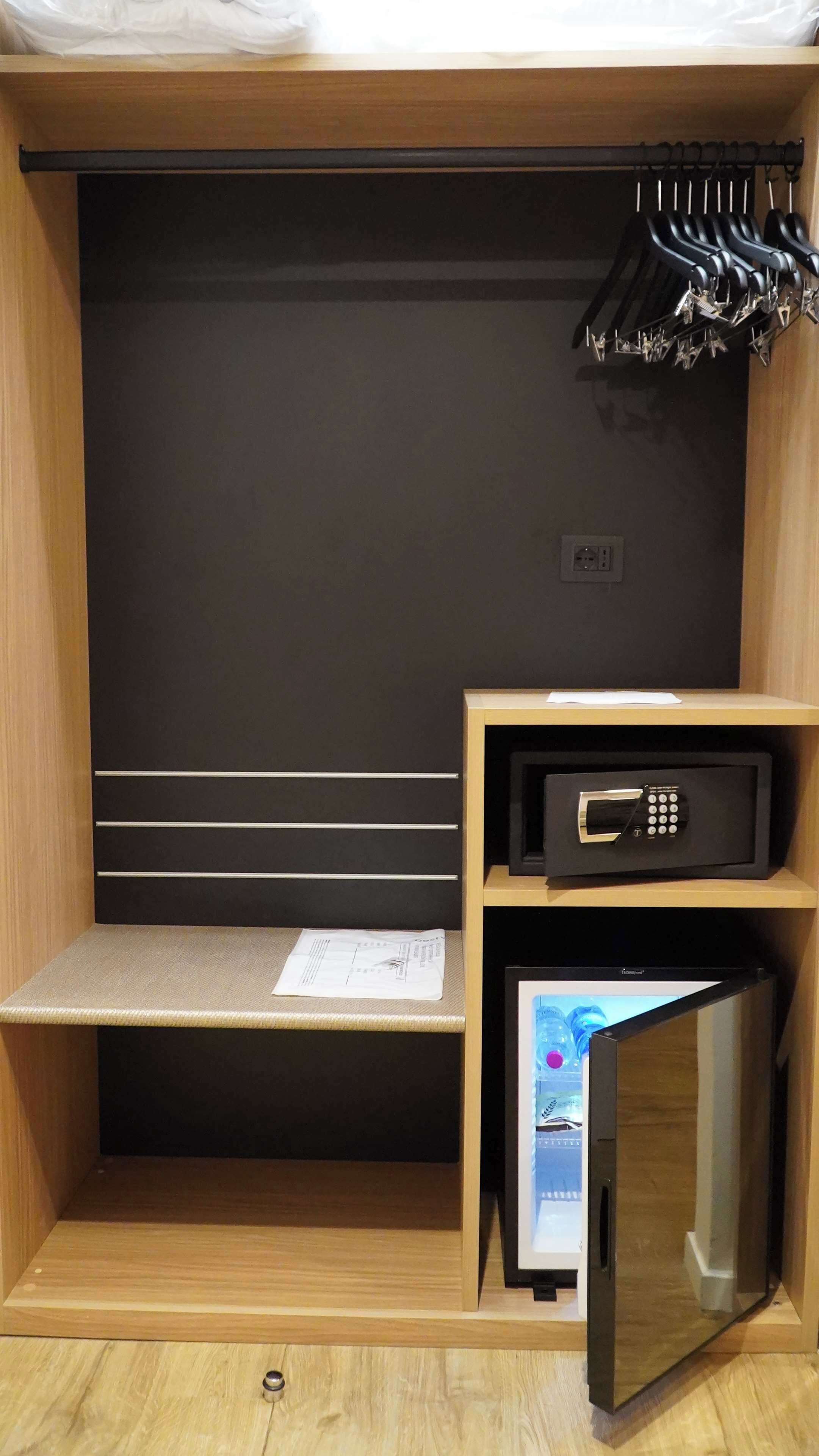 A compact room with a bed, a small desk, a microwave, and a TV.
