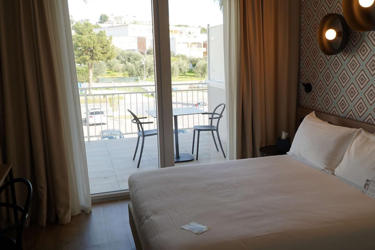 Habitación de hotel con cama, una mesa y sillas, y vistas al exterior.