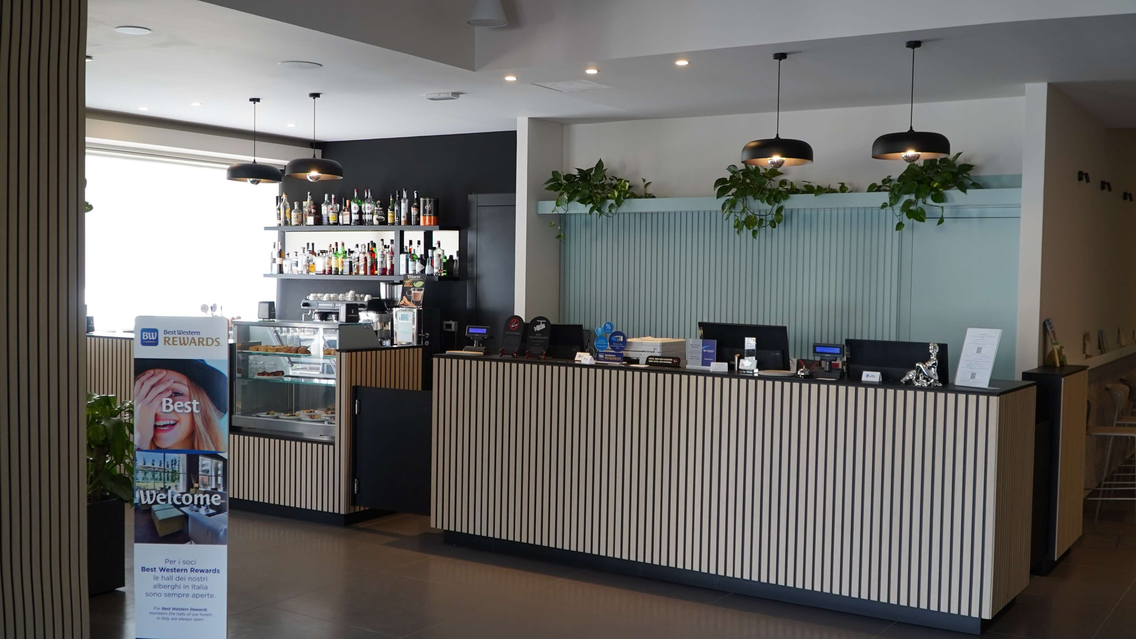 A modern reception desk with a glass display case, a coffee machine, and a plant.
