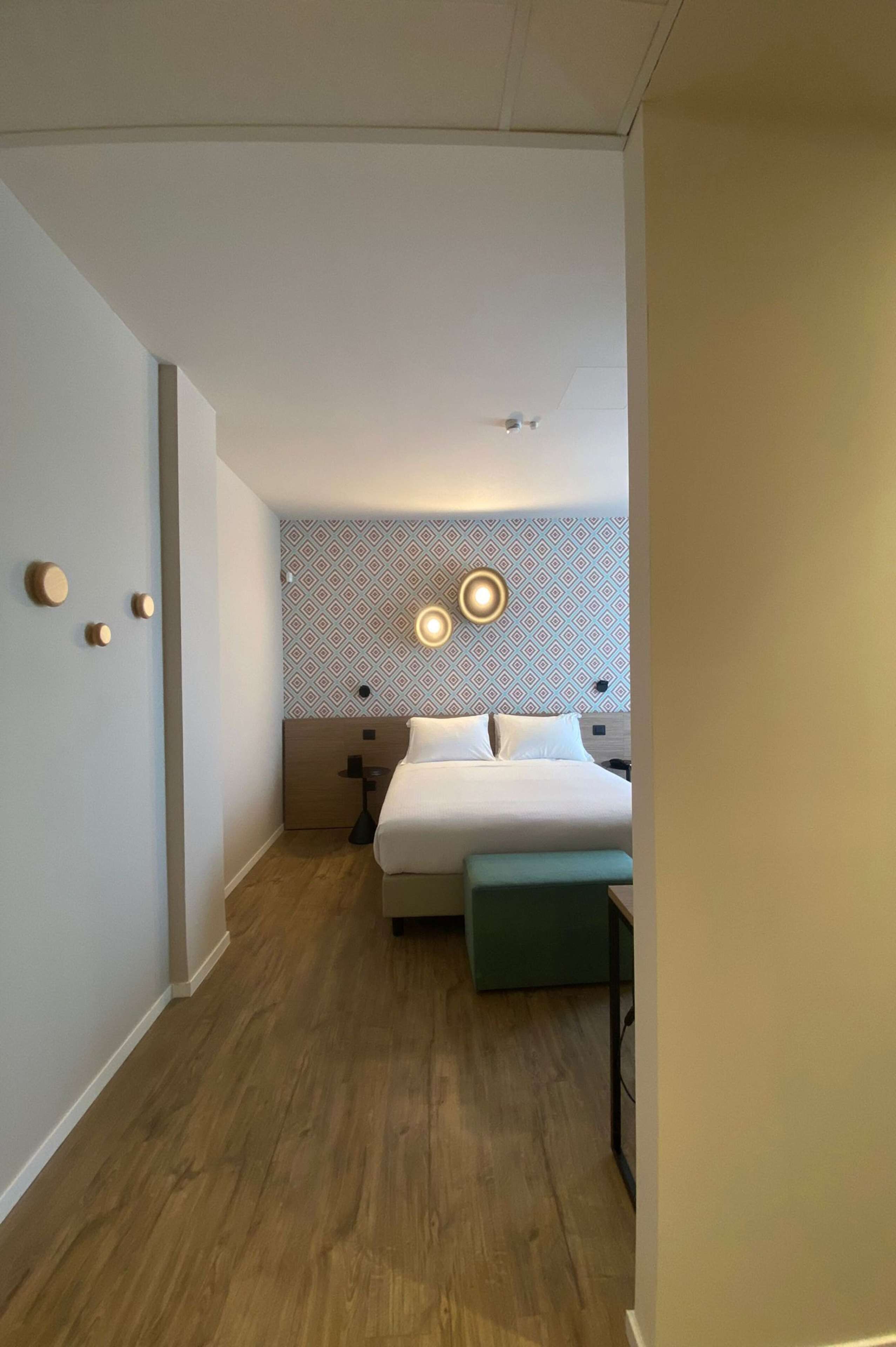 Una habitación de hotel con cama, mesitas de noche y un papel tapiz estampado.