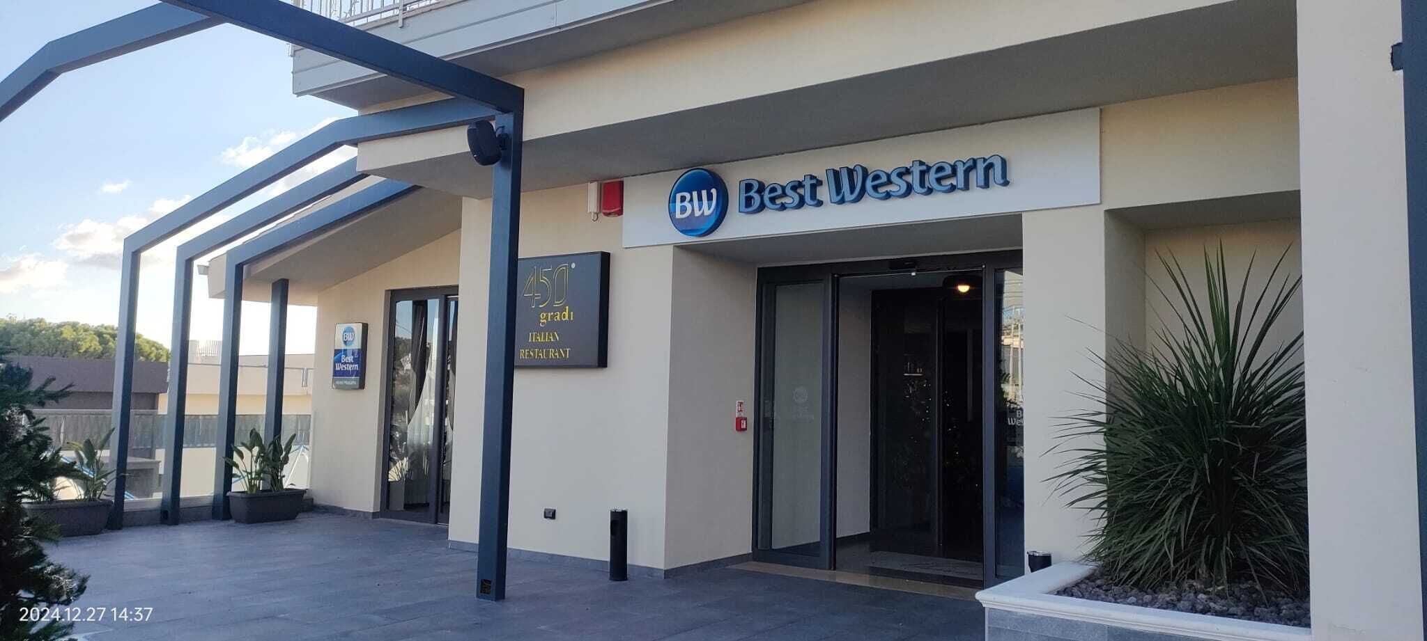 Un restaurante italiano Best Western con fachada moderna, mesas al aire libre y cielo despejado.
