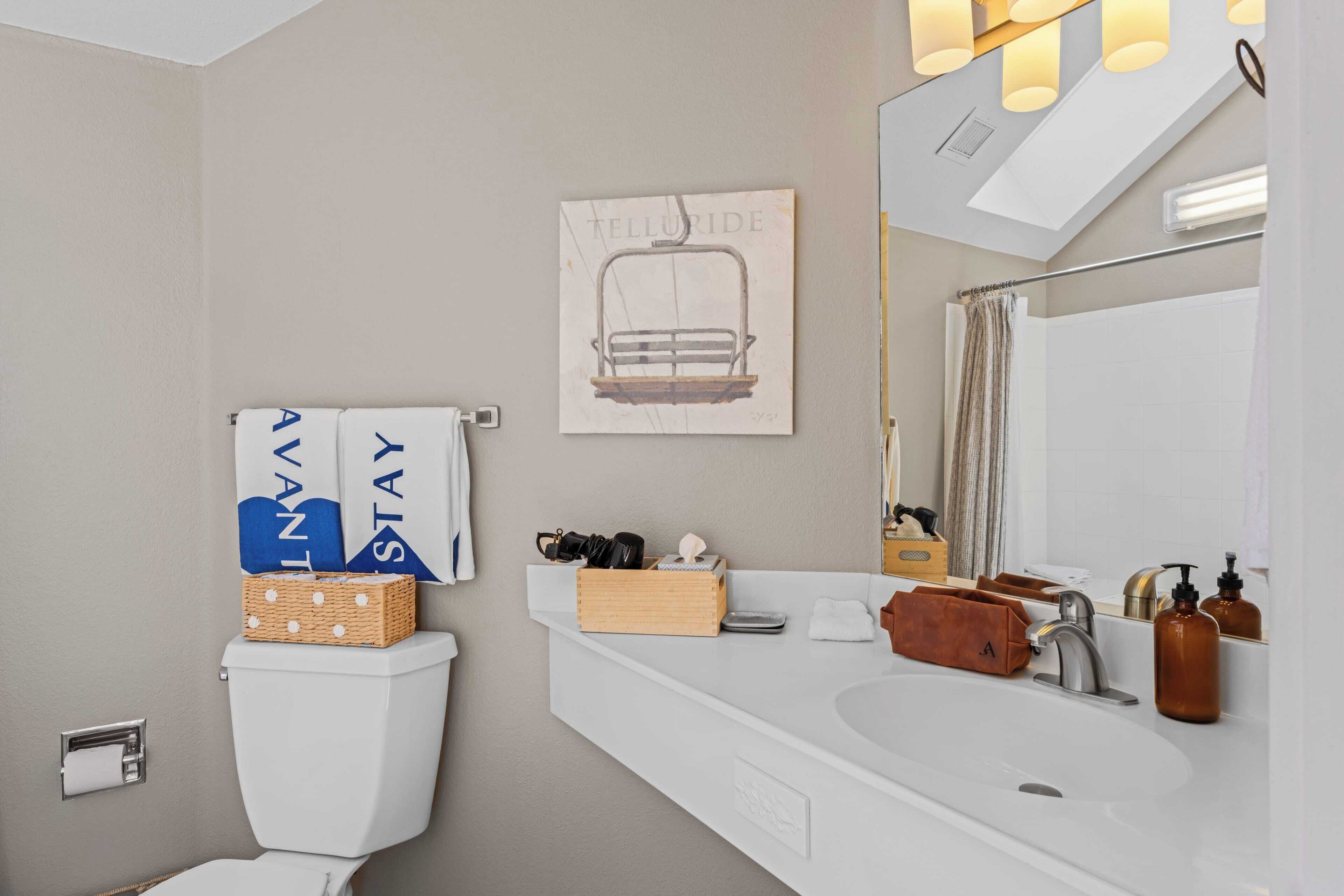 A modern bathroom with a toilet, sink, and mirror.