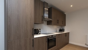 Una cocina moderna con armarios de madera, microondas, hervidor y horno.