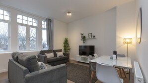 Una sala de estar moderna con sofá, televisión, mesa de comedor y lámpara.