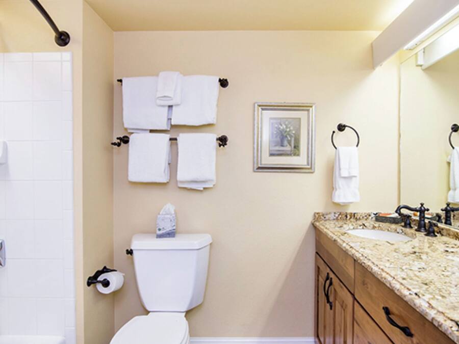 A bathroom with a toilet, sink, mirror, and shower.