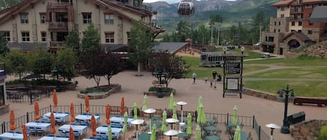 Un hôtel doté d’une terrasse, une enseigne indiquant « Sunset Plaza », et une chaîne de montagnes en arrière-plan.