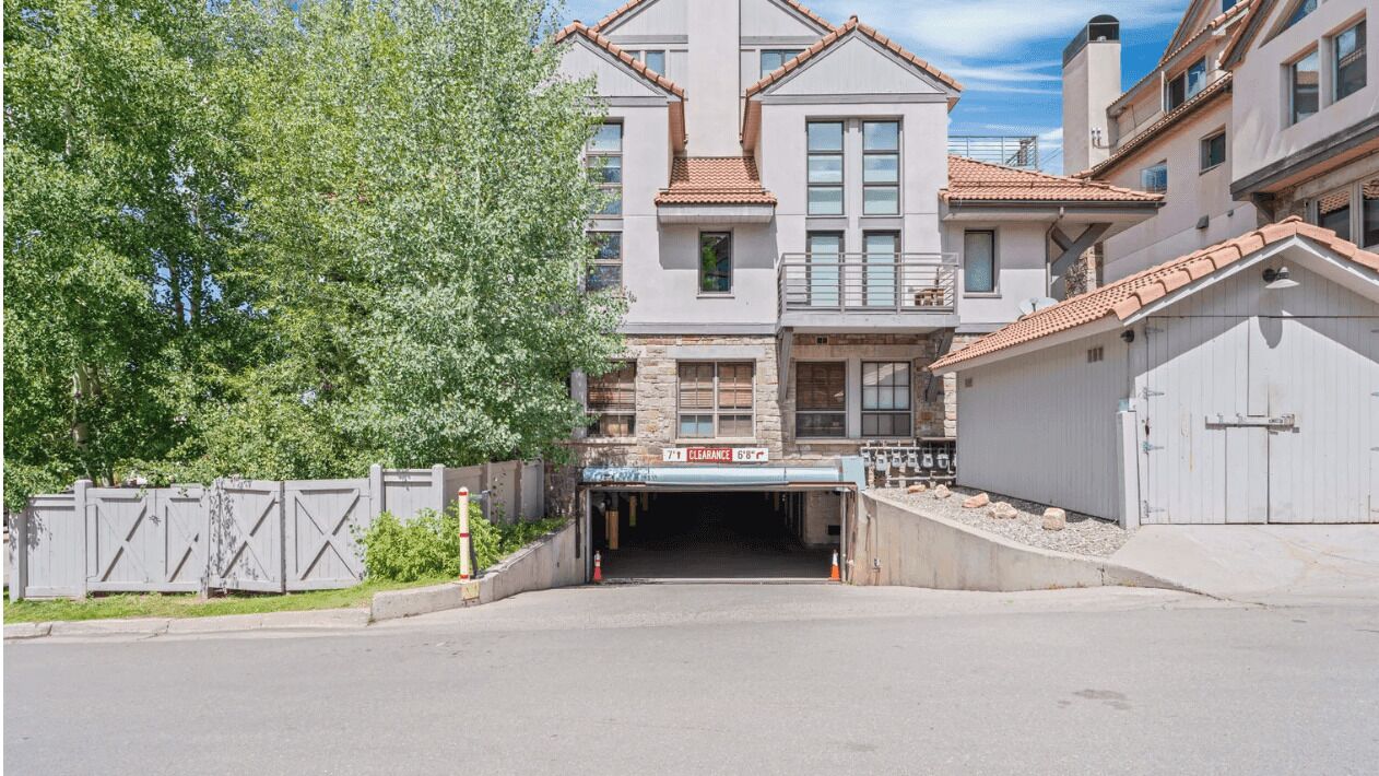 A gated driveway leading to a building with multiple windows and a tiled roof.